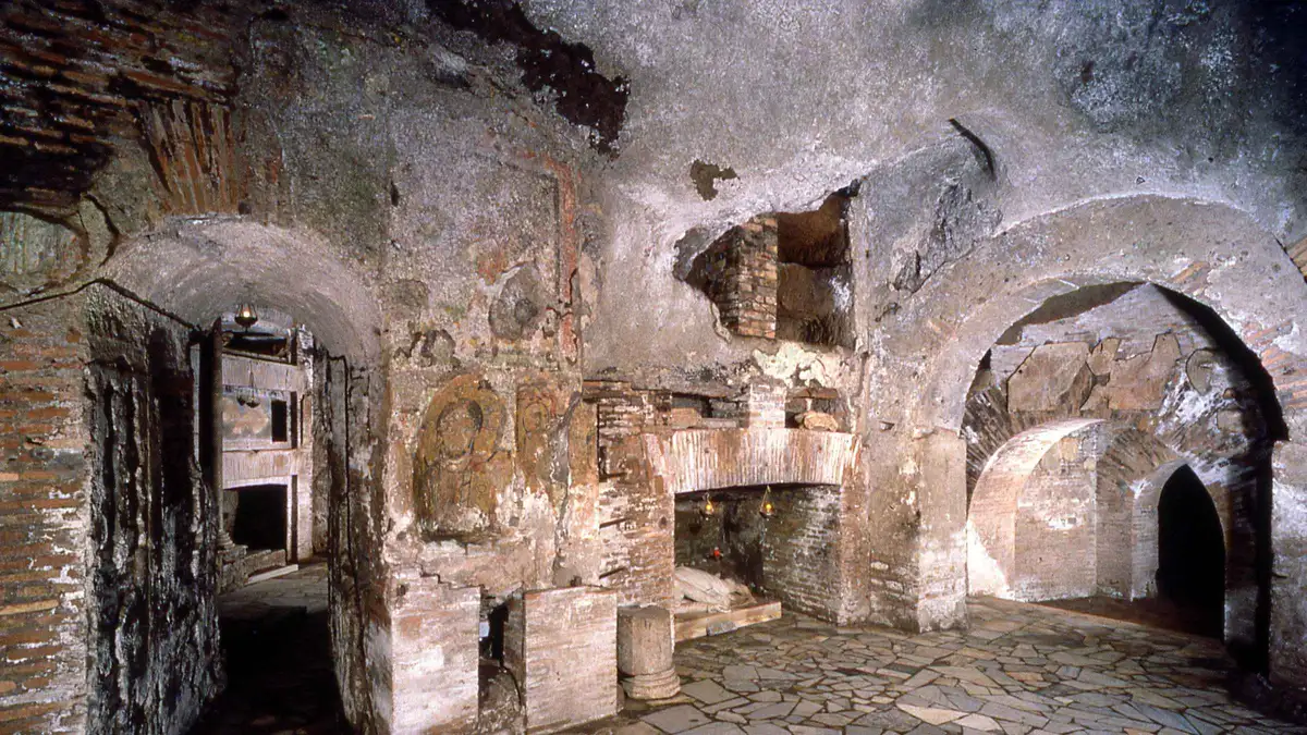 Guided group descending stone steps into the Catacombs of St. Callixtus on a Rome underground tour of the Appian Way