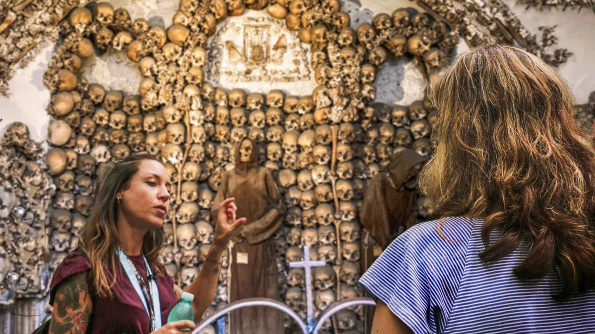 Guide leading visitors past burial niches on a Rome underground tour of the catacombs and crypts